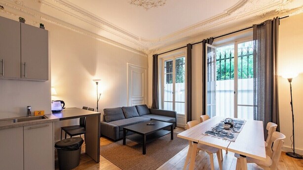 A modern living room with a sofa, coffee table, dining table, and kitchen area. - Central 1BR Quai de Seine in the Marais district (Paris)
