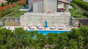 A pool area with lounge chairs and a blue umbrella, surrounded by stone walls and greenery. - Beautiful private villa for 5 people with A/C, private pool, WIFI, TV and patio (Umag)