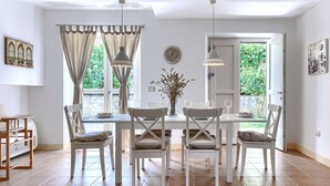 A dining area with a table set for four, white chairs, a vase with flowers, and a view of greenery outside. - Beautiful private villa for 5 people with A/C, private pool, WIFI, TV and patio (Umag)