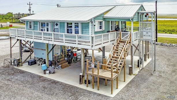 A two-story building with a balcony and a wooden staircase. - Cocodrie Waterfront Fishing Camp - Sportsmans Paradise (Chauvin)