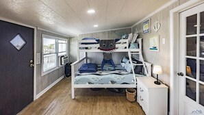 A bunk bed room with a ceiling fan, a window, and a door with glass panels. - Cocodrie Waterfront Fishing Camp - Sportsmans Paradise (Chauvin)