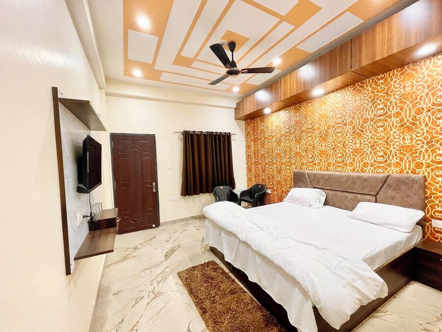 A bedroom with a bed, a ceiling fan, a TV, and patterned wallpaper.