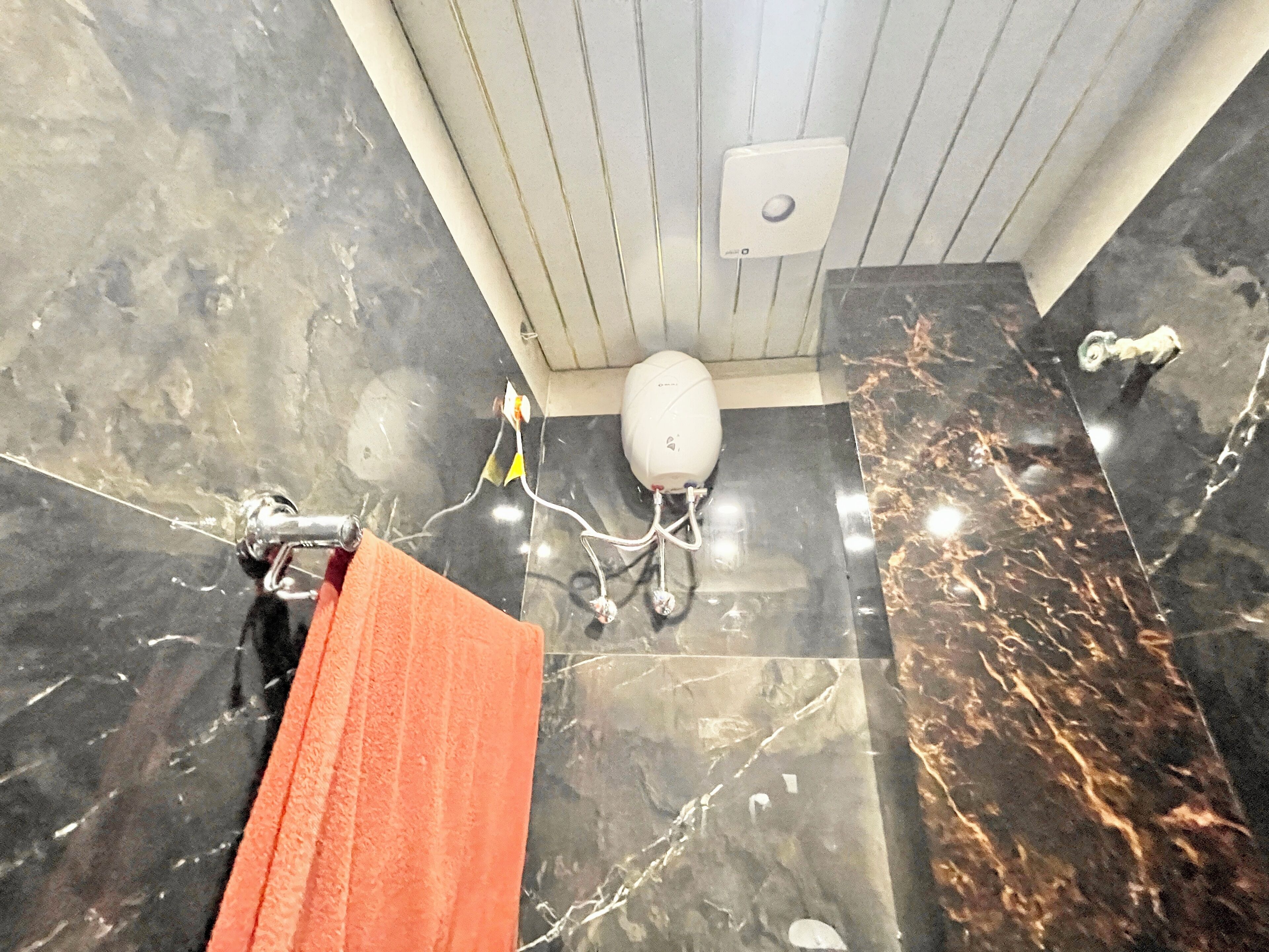 A bathroom with a marble floor, a white toilet, and a towel rack.