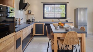 Eine moderne Küche mit Holzschränken, einer schwarzen Arbeitsplatte und einem großen Fenster.