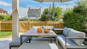 Eine Außenpatio mit Tisch, Stühlen und einem großen Sonnenschirm.