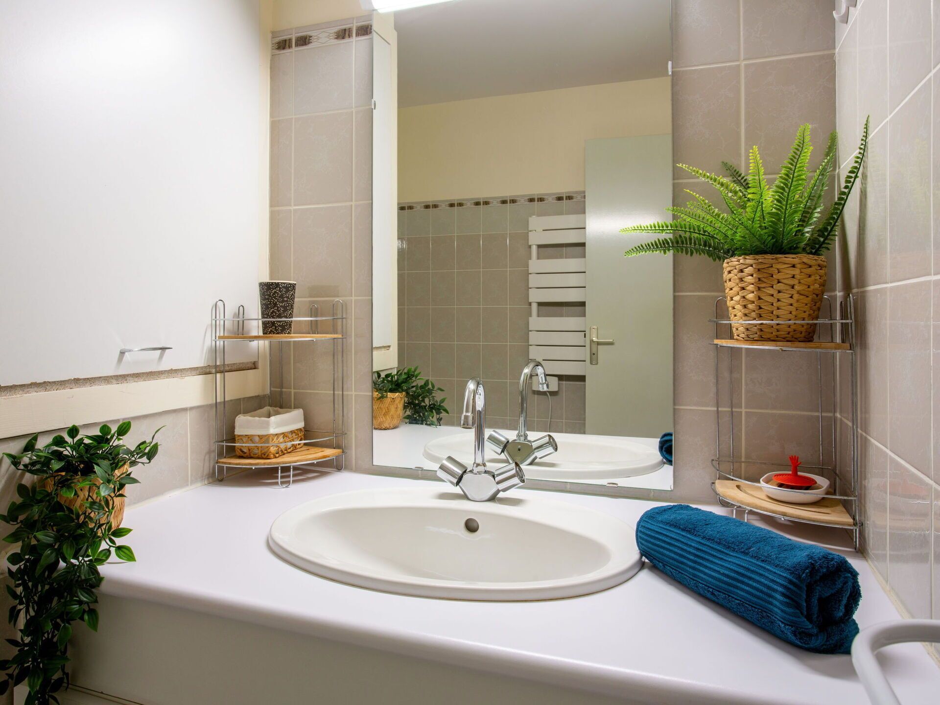 A modern bathroom with a white sink, a mirror, and a towel rack.