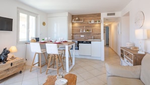 Cocina moderna con armarios blancos, encimera de madera y zona de comedor con cuatro sillas blancas y una mesa preparada para cuatro comensales.
