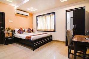A bedroom with a bed, bedside tables, a desk, and a chair. - Fabhotel Gr Hospitality (Barasat)