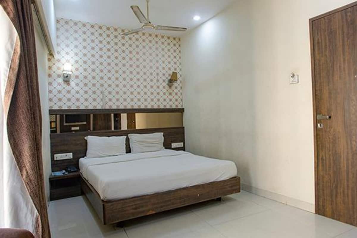 A bedroom with a wooden bed, a ceiling fan, and a patterned wallpaper.