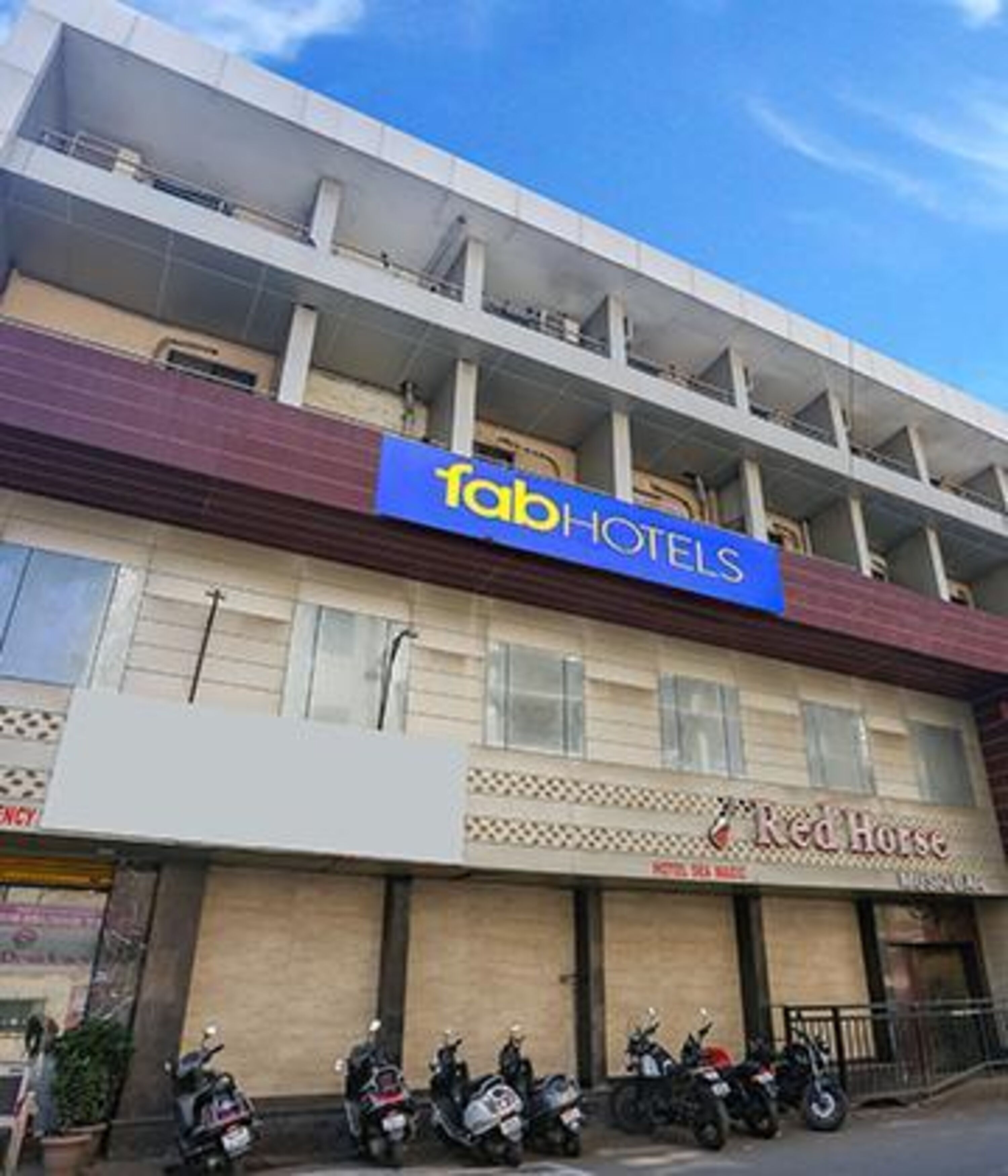A building with a 'Tab Hotels' sign and a 'Red Horse' restaurant. There are several motorcycles parked in front.