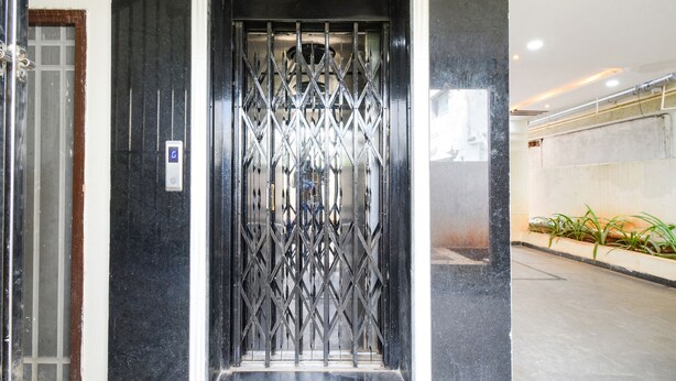 A modern elevator with a metal security gate, a digital display, and a marble wall.