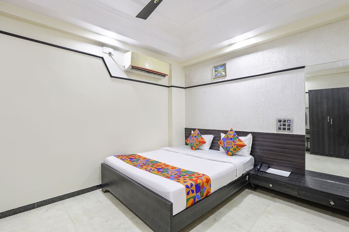 A modern hotel room with a bed, bedside table, and a large mirror.
