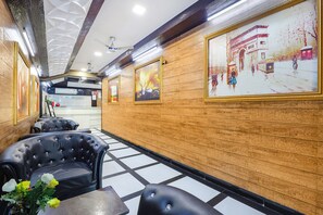 A hotel lobby with wooden paneling, black leather seating, and framed artwork on the walls. - Fabhotel Apple Inn (Ahmedabad)