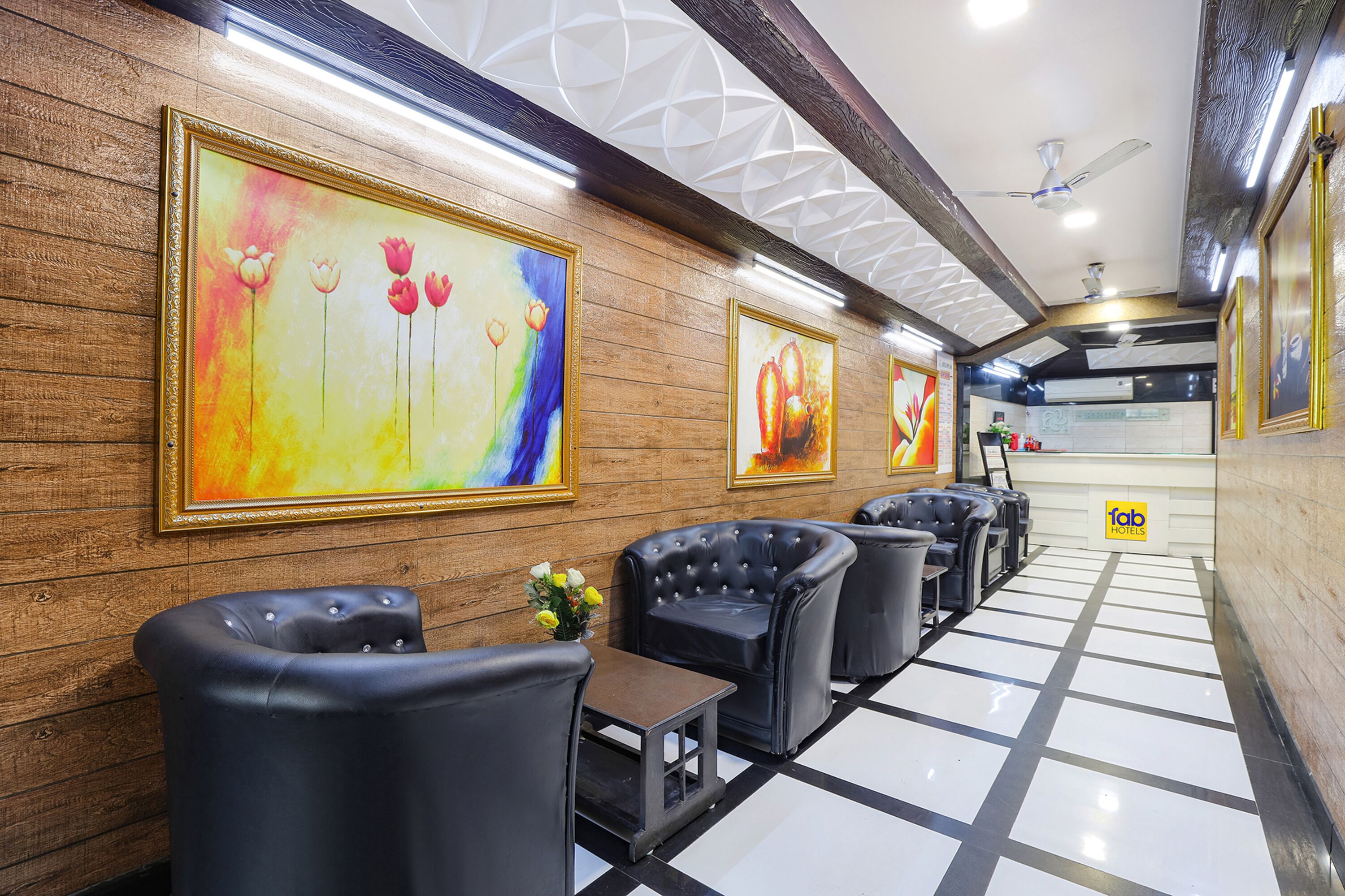 A hotel lobby with wooden paneling, black leather seating, and colorful artwork on the walls.