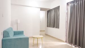 Un salon moderne avec un canapé de couleur turquoise, une petite table ronde et une lampe.