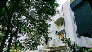 Un immeuble à plusieurs étages, doté d’une façade blanche, de balcons et de plantes en pot.