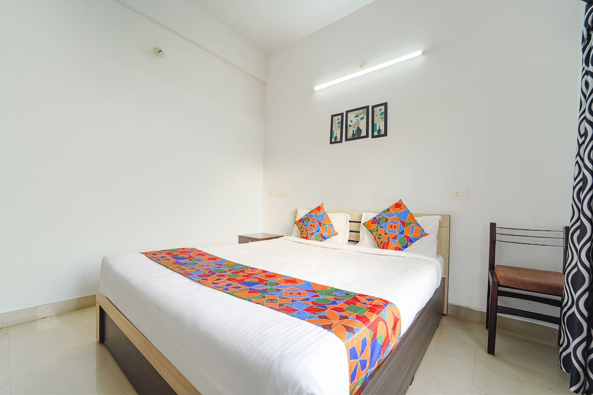 A neatly made bed with a colorful blanket, a bedside table, and a chair.