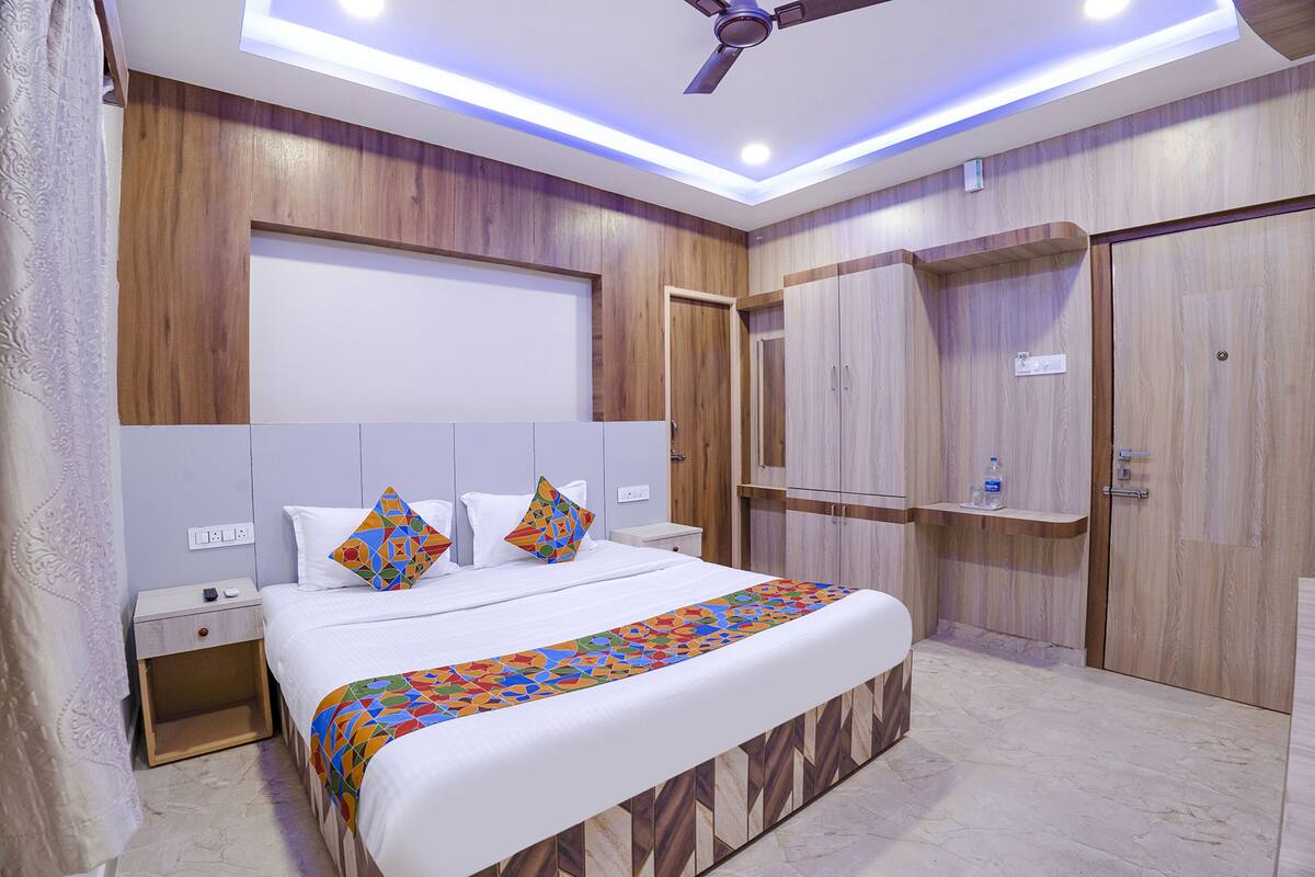 Un dormitorio moderno con cama, mesitas de noche, ventilador de techo, armarios empotrados y colcha estampada.