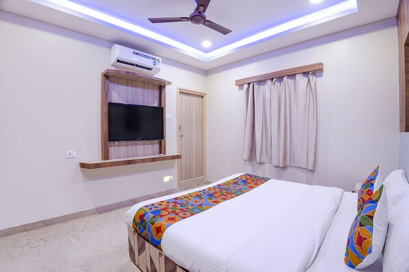 A bedroom with a bed, a ceiling fan, an air conditioning unit, a window with curtains, and a TV mounted on the wall. - Fabhotel Wooden Park (Chennai)