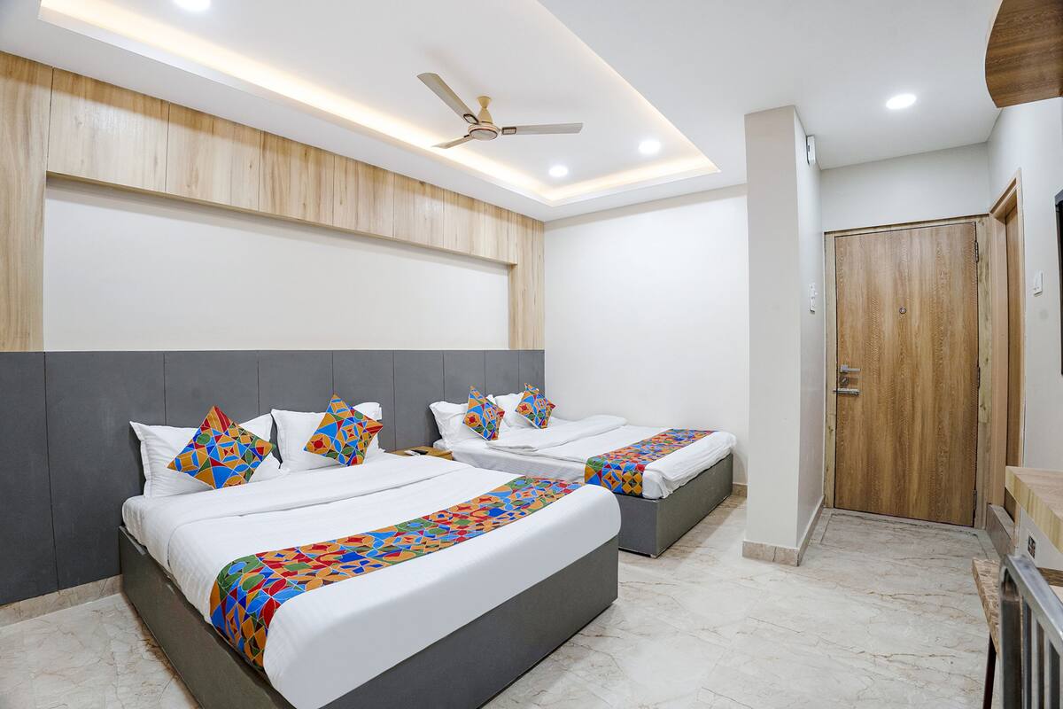 Una habitación de hotel moderna con dos camas, un ventilador de techo y una puerta de madera.