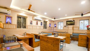 Un restaurante con mobiliario de madera, ventiladores de techo y una televisión de pantalla plana.
