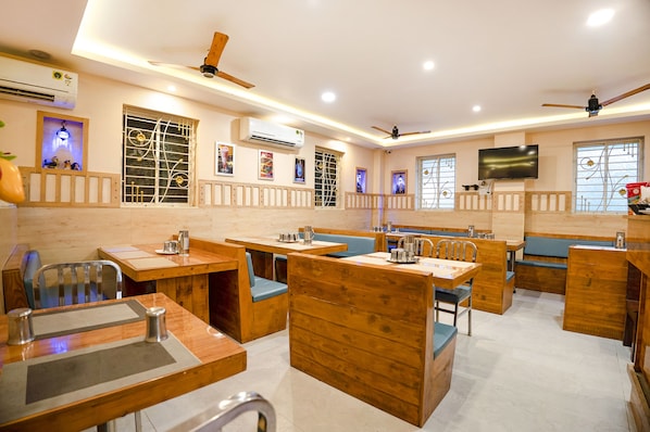 A restaurant with wooden furniture, ceiling fans, and a flat-screen TV.