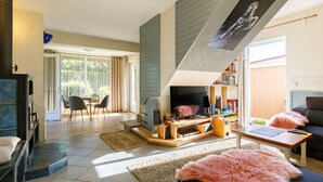 Una sala de estar moderna con chimenea, televisor y comedor con sillas y mesa.
