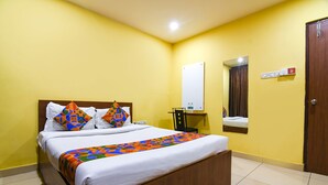 Une chambre d’hôtel avec un lit, un miroir, une porte et un luminaire fixé au mur.