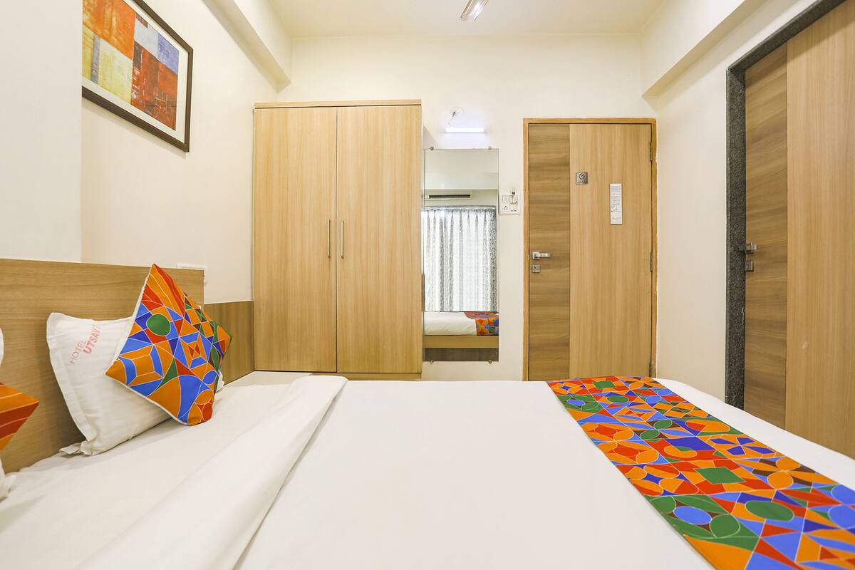 A hotel room with a bed, a wardrobe, and a bathroom visible through an open door.