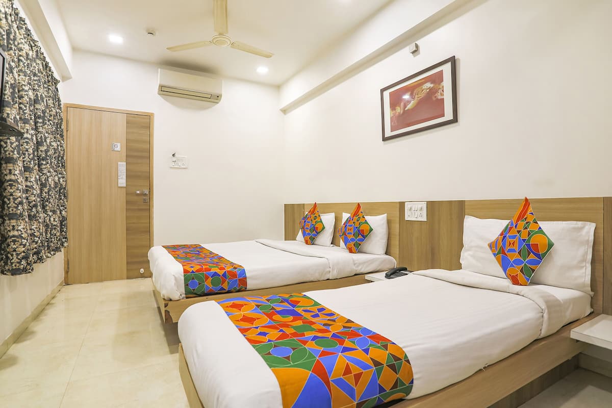 A hotel room with two beds, a ceiling fan, an air conditioner, and a framed picture on the wall.