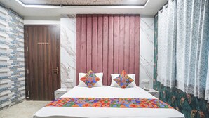 Une chambre à coucher avec un lit, deux oreillers, une table de chevet, une porte en bois et des rideaux à motifs.