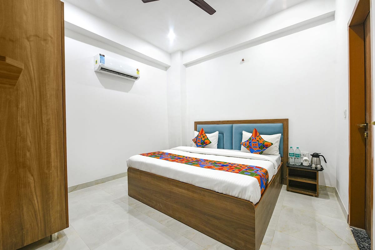 A hotel room with a wooden bed, white walls, and a ceiling fan.