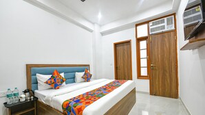 A bedroom with a bed, wooden wardrobe, and a small bedside table with toiletries. - FabHotel Blue Stone Stay (Gurugram)