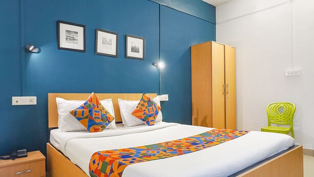 A hotel room with a bed, a wardrobe, a chair, and three framed pictures on the wall. - FabHotel Silver Key (Pune)