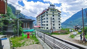 A multi-story building with a flat roof, surrounded by greenery and mountains. - Fabhotel Arigato Cottage (Manali)