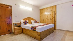 A bedroom with a wooden bed, a nightstand, a wooden wardrobe, and a tiled floor. - Fabhotel Arigato Cottage (Manali)