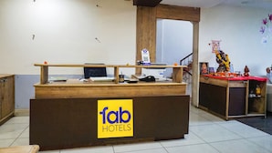 Un comptoir d’accueil avec une enseigne indiquant « fab hotels » et un petit autel où sont déposées des offrandes.