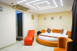 Ein Hotelzimmer mit Bett, Sessel, Nachttisch und Tür.