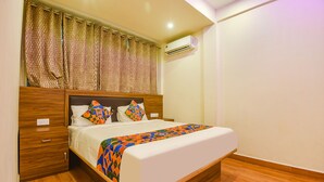 Ένα στρωμένο κρεβάτι με προσεγμένο τρόπο, με ένα διακοσμητικό κάλυμμα, ένα ξύλινο προσκέφαλο και ένα κομοδίνο με ένα συρτάρι.