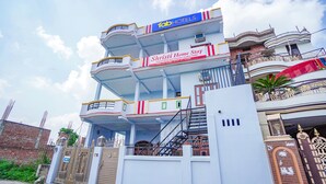 A multi-story building with balconies, a gated entrance, and signage for 'Tab Hotels' and 'Shristi Home Stay'. - Fabhotel Shristi Homestay (Faizabad)