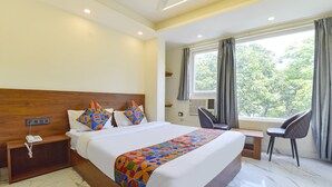 A hotel room with a large bed, a desk, a chair, a phone on the nightstand, and a window with curtains. - Fabhotel Uv (Rishikesh)