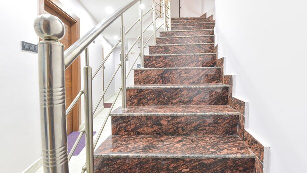A marble staircase with metal railings and a door at the top. - Fabhotel Uv (Rishikesh)