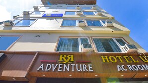 A multi-story building with a sign for "RA ADVENTURE AC ROOM" and "TOB HOTELS" on the facade. - Fabhotel Uv (Rishikesh)