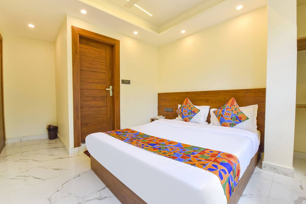 A hotel room with a large bed, a wooden headboard, and a marble floor.