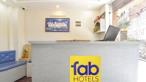 A reception desk with a 'fab hotels' sign, a framed painting of horses, and a laptop on the counter. - Fabhotel Uv (Rishikesh)