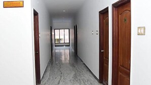 Un pasillo con puertas de madera, un cartel que indica el primer piso y un ventanal al final.