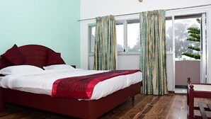Un dormitorio con cama, ventana con cortinas y vista a follaje exterior.