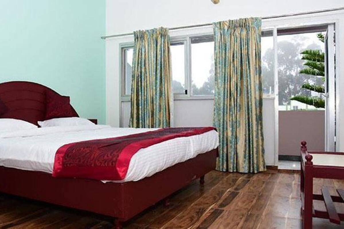 Una camera da letto con un letto, una finestra con tende e vista su del verde all'esterno.