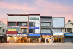 A row of commercial buildings with various businesses including a hotel, a restaurant, and a furniture store. - FabExpress Galaxy II (Faridabad)