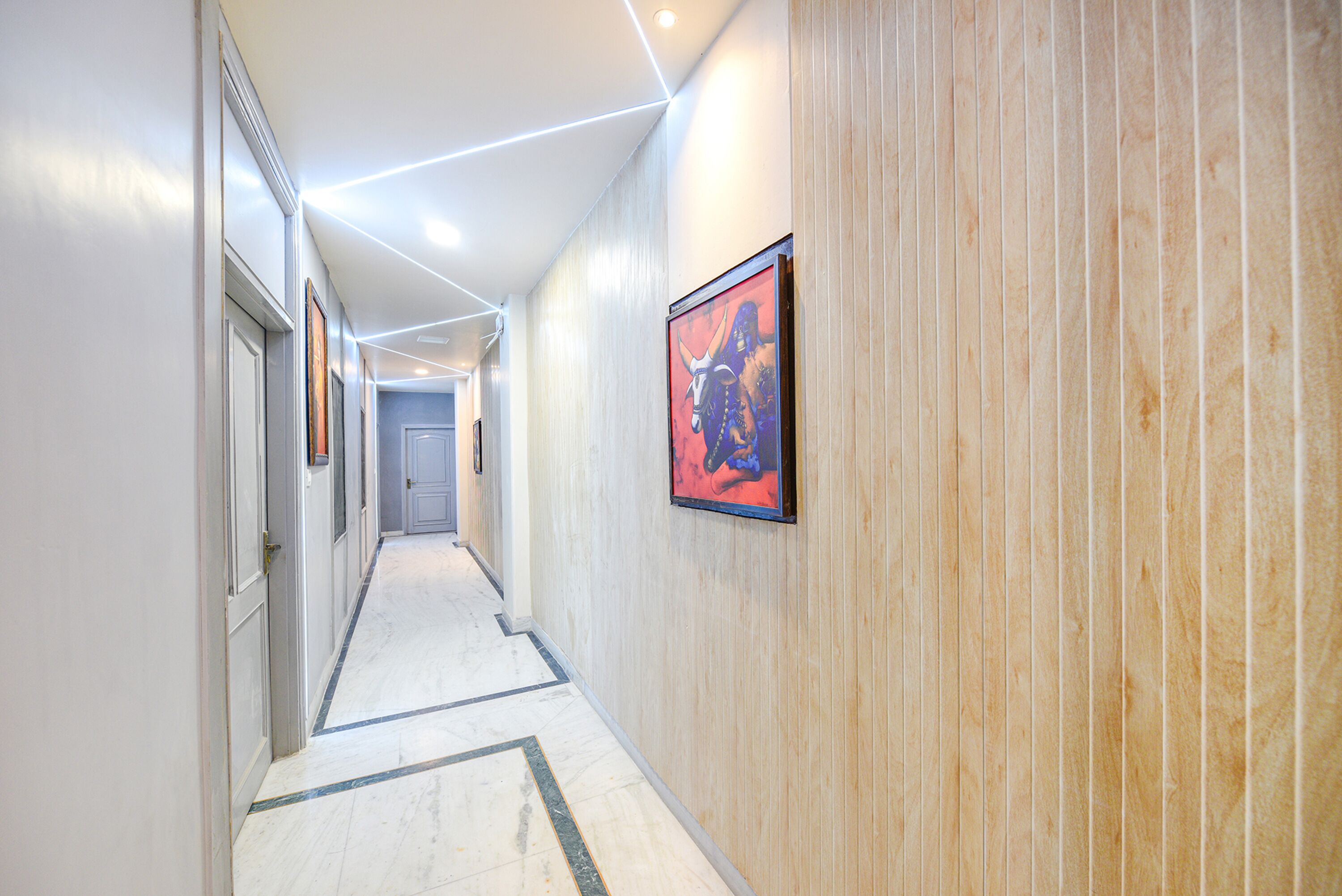 A hallway with wooden paneling, a framed picture on the wall, and a geometric patterned floor.